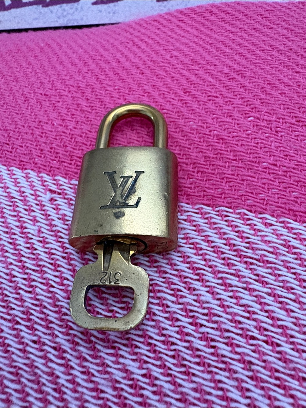 Louis Vuitton Gold-tone Padlock with Key on Pink Background
